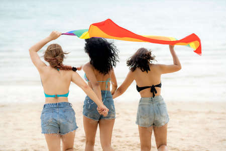 Group of LGBTQ woman ran and play togather with LGBT flag on the beachの写真素材