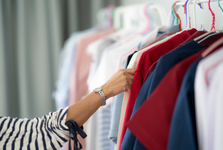 woman hand shopping and select T-shirts from clothes shop in department store