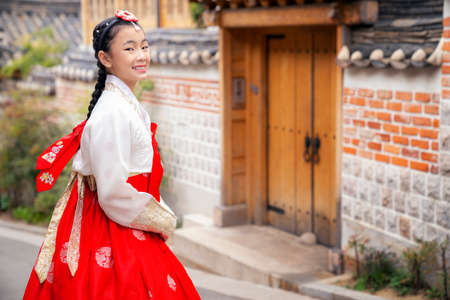 Asian woman traveler in traditional korean dress or hanbok dress walking in old palace with sakura flower background, Seoul city, South Koreaの写真素材