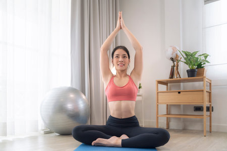 Asian woman exercise and stretching in her bed room, her try to make slim by take Yoga, cardio, fitness at home between quarantineの写真素材
