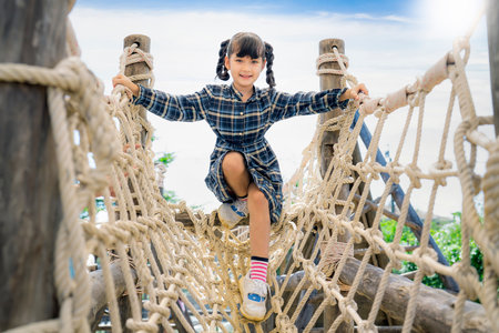 Asian preschool girl playing on playground in her school, group of Thai kids play togather at play groundの写真素材