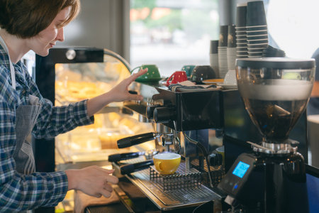 Women barista in an apron making coffee with coffee maker machine in a coffee shopの写真素材