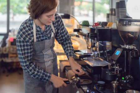 Women barista in an apron making coffee with coffee maker machine in a coffee shopの写真素材