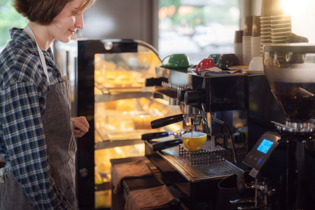 Women barista in an apron making coffee with coffee maker machine in a coffee shopの写真素材