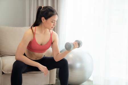 Asian woman exercise and stretching in her bed room, her try to make slim by take Yoga, cardio, fitness at home between quarantineの写真素材