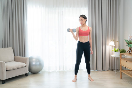 Asian woman exercise and stretching in her bed room, her try to make slim by take Yoga, cardio, fitness at home between quarantineの写真素材