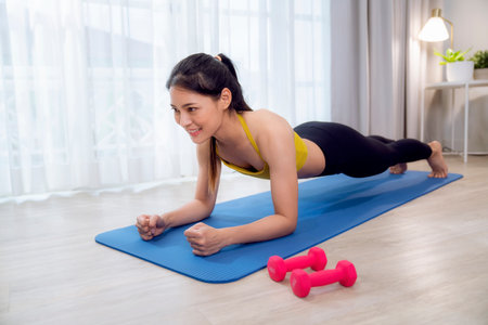 Asian woman exercise and stretching in her bed room, her try to make slim by take Yoga, cardio, fitness at home between quarantineAの写真素材