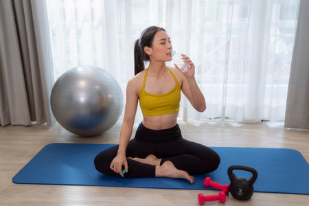 Asian woman exercise and stretching in her bed room, her try to make slim by take Yoga, cardio, fitness at home between quarantineの写真素材