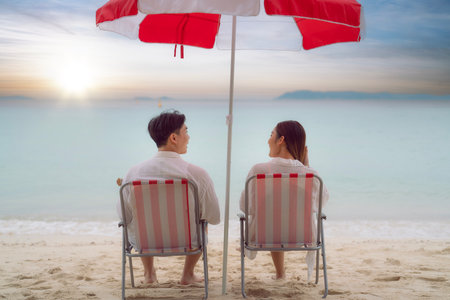 Asian traveller couple sitting and see sunset togather on the beach with longtail boat background at Phi phi island maya beach near Phuket, Thailandの写真素材