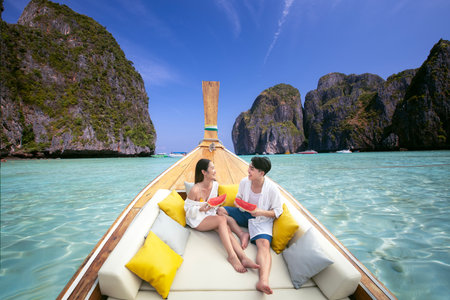 Asian couple lover travel and relax in they honeymoon trip on the wooded boat at Krabi, Phi Phi island, maya bay, Thailandの写真素材