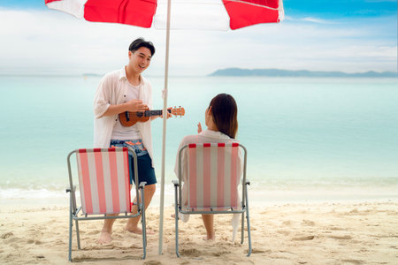Asian traveller couple sitting and see sunset togather on the beach with longtail boat background at Phi phi island maya beach near Phuket, Thailandの写真素材