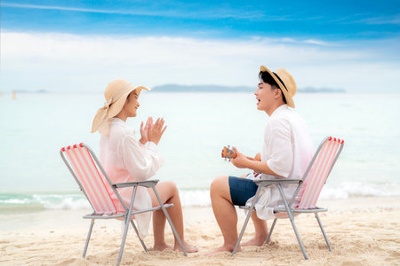 Asian traveller couple sitting and see sunset togather on the beach with longtail boat background at Phi phi island maya beach near Phuket, Thailandの写真素材