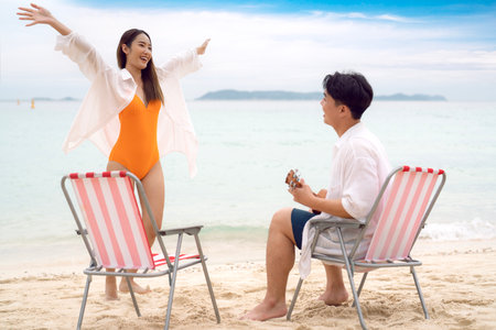 Asian traveller couple sitting and see sunset togather on the beach with longtail boat background at Phi phi island maya beach near Phuket, Thailandの写真素材