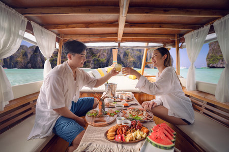Asian couple lover travel and relax in they honeymoon trip on the wooded boat and eat seafood togather at Koh phi phi island, Maya beach, Phang nga near Phuket in Thailandの写真素材