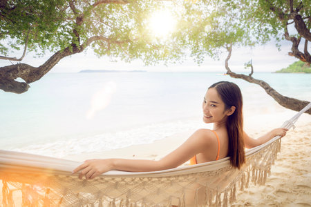 Asian woman traveller sleep on the swing cragle with bikini on the beach at Pataya Beach, Thailandの写真素材