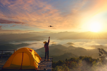 A woman use drone for take a photo landscape between sunrise  and fog background at top of mountain at Tak near Chiang mai, Thailandの写真素材
