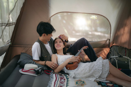 Asian couple sweet in tent inside on they camping trip, traveller relax and sleep togather in out door and camping tripの写真素材