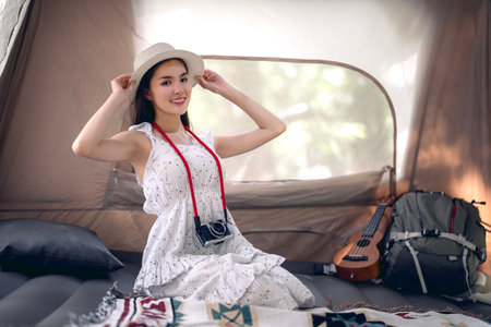 Asian traveller and photographer relax with her camera in camping trip inside her tentの写真素材
