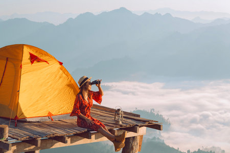 Asian traveller woman take a photo by her camera on the top of mon Kalakojo at Tak with sunrise and...