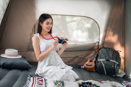 Asian traveller and photographer relax with her camera in camping trip inside her tentの写真素材