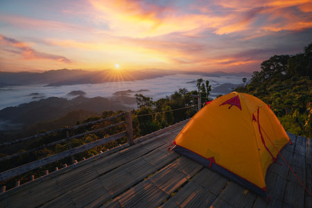 Asian traveller woman take a photo by her camera on the top of mon Kalakojo at Tak with sunrise and fog background on the morning time, Winter season of view point near Chiang mai, Thailandの写真素材