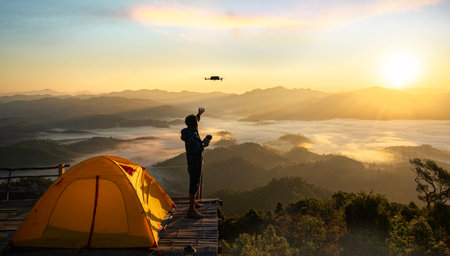 A man use drone for take a photo landscape between sunrise  and fog background at top of mountain at Tak near Chiang mai, Thailandの写真素材