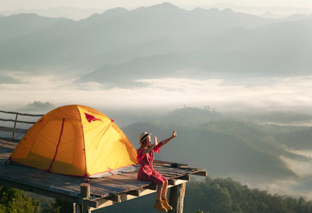 Asian traveller woman take a photo by her camera on the top of mon Kalakojo at Tak with sunrise and fog background on the morning time, Winter season of view point near Chiang mai, Thailandの写真素材