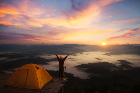 Asian traveller woman take a photo by her camera on the top of mon Kalakojo at Tak with sunrise and fog background on the morning time, Winter season of view point near Chiang mai, Thailandの写真素材
