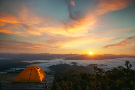Asian traveller woman take a photo by her camera on the top of mon Kalakojo at Tak with sunrise and fog background on the morning time, Winter season of view point near Chiang mai, Thailandの写真素材
