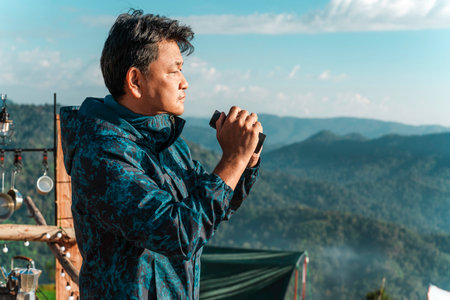 Asian traveler man use binoculars between his camping trip in north of Thailandの写真素材