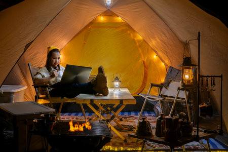 Asian woman enjoy in they tent in camping trip on night time with many star on the sky, they enjoy coffee, working by coputer notebook and not book and relax in campの写真素材