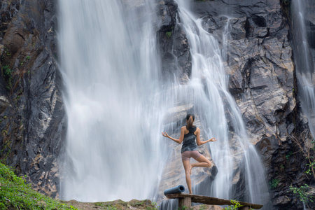 Asian traveller woman pose yoga in lotus pose with waterfall background at Chiangmai, Thailandの写真素材
