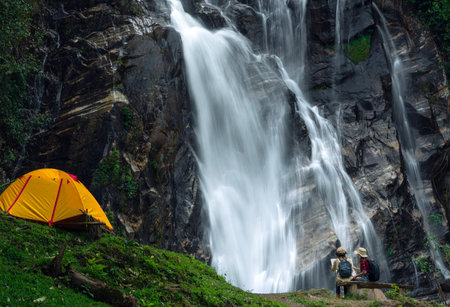 woman traveller walk togather Tent and camping with Mae Tia waterfall and mountain background at inthanon national park in Chiang mai, Thailand, un seen travel point for camping and relax in holidayの写真素材