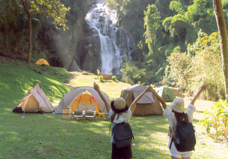 woman traveller walk togather Tent and camping with Mae Tia waterfall and mountain background at inthanon national park in Chiang mai, Thailand, un seen travel point for camping and relax in holidayの写真素材