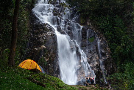 woman traveller walk togather Tent and camping with Mae Tia waterfall and mountain background at inthanon national park in Chiang mai, Thailand, un seen travel point for camping and relax in holidayの写真素材
