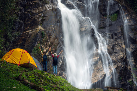 woman traveller walk togather Tent and camping with Mae Tia waterfall and mountain background at inthanon national park in Chiang mai, Thailand, un seen travel point for camping and relax in holidayの写真素材