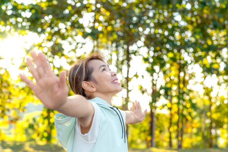 middle age Asian woman in sportswear action yoga in park and green nature on morning timeの写真素材