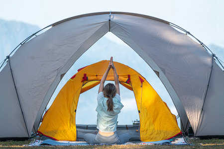 Asian traveller woman post yoga in tent on her camping with mountain and outdoor backgroundの写真素材