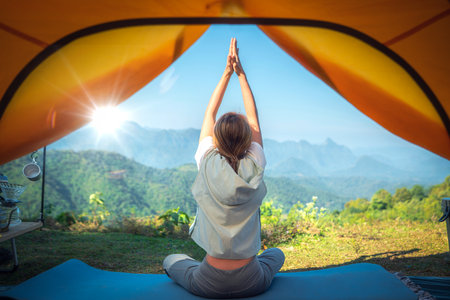 Asian traveller woman post yoga in tent on her camping with mountain and outdoor background in Thailandの写真素材
