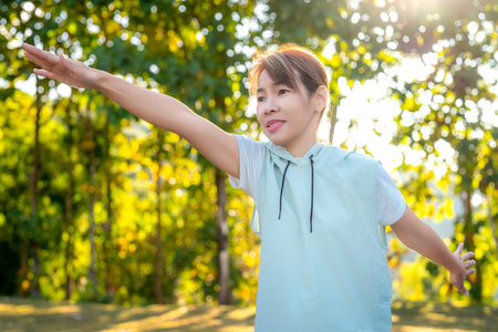 middle age Asian woman in sportswear action yoga in park and green nature on morning timeの写真素材