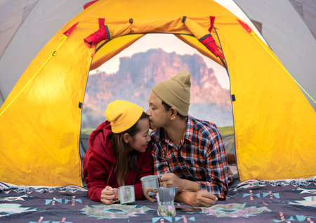 Asian couple sweet in tent in camping with moutain background in Thailandの写真素材