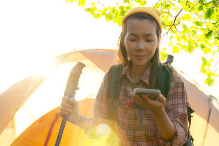 hobby and outdoor activities concept. middle age female pensioner enjoying beautiful wild nature and use navigator from smartphone, using sticks for nordic walking, spending summer weekend away from city noisesの写真素材