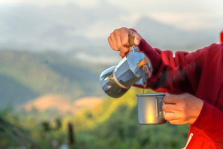 Traveller woman sit on the roof top tarp and car and drink a coffee with morning sunrise and fog on the mountain view, Chiangmai, Thailandの写真素材