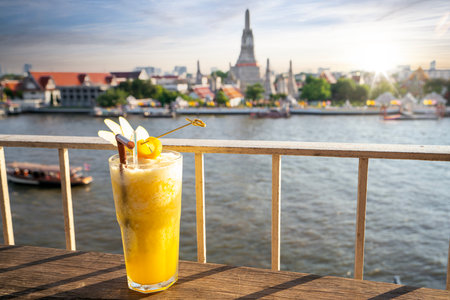 Juice beverages in the rooftop bar with Wat arun and Arun pagoda and sunset background in Bangkok city, Thailandの写真素材