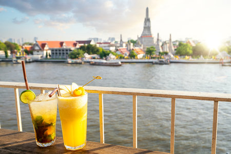Juice beverages in the rooftop bar with Wat arun and Arun pagoda and sunset background in Bangkok city, Thailandの写真素材