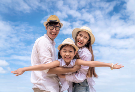 Asian family father, mother and daughter playing togather in fly action with beach and summer background in holiday timeの写真素材