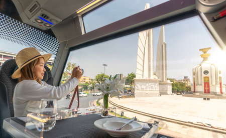 Asian traveller woman take a photo the Thailand democracy monument on the restaurant bus between city tour by busの写真素材