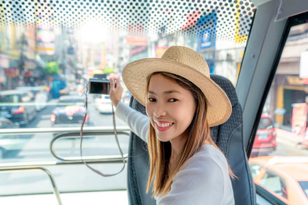 Asian woman travel and tour in Bangkok city on  yaowarat road area by restaurant bus and take a photo by her smart phoneの写真素材