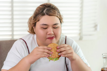 Asian over size fat woman enjoy over eating on the restaurant, un healthy foods and junk food concept photoの写真素材