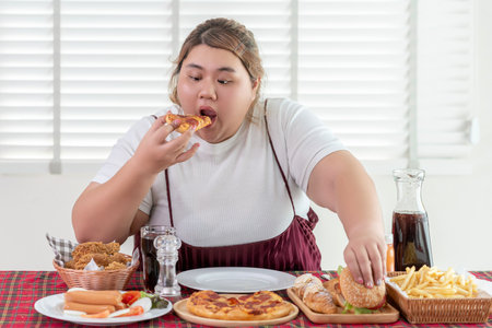 Asian over size fat woman enjoy over eating on the restaurant, un healthy foods and junk food concept photoの写真素材